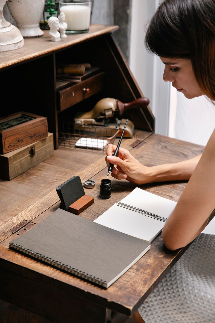 Travel essayist writing at desk with field gear